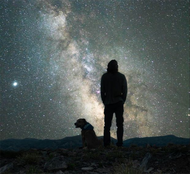 Dog owner and his dog stargazing on a dog walk